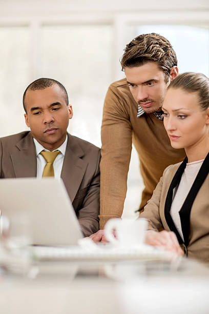 istock Serious business people using laptop together in the office. 486779452