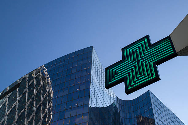 Pharmacy sign Green pharmacy sign contrasting with the office buildings around in La Défense, Paris. France outer paris stock pictures, royalty-free photos & images