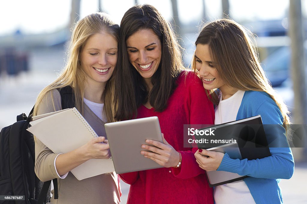 Students having fun with smartphones and tablets after class A group of students having fun with smartphones and tablets after class Adult Stock Photo