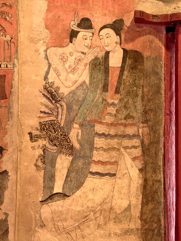 The famous mural painting of a man whispering to the ear of a woman in ancient Buddhist temple - Wat Phumin, Nan province, Thailand. 