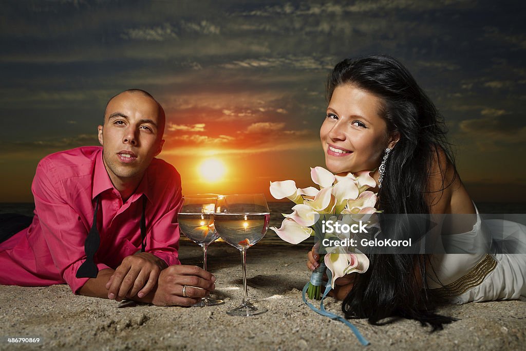 bride and groom at sunset Portrait of bride and groom with golden fish making wish at sunset on sea Adult Stock Photo