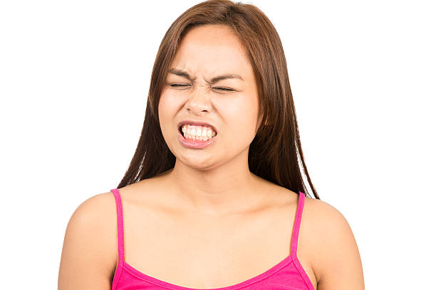 Angry Asian Woman Gritting Teeth Closed Eyes H A cute angry Asian woman, eyes closed, wearing pink sleeveless tank top, grimacing, gritting teeth in anger, frustration, irritation, bothered. Horizontal clenching teeth stock pictures, royalty-free photos & images