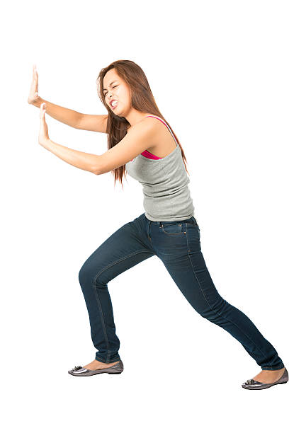 Woman Extended Arms Pushing Against Side Object Struggling Asian woman in casual clothes, extended arms, defending, protecting, forcing, leaning body weight, pushing and fighting against imaginary (insert) object moving in from side sleeveless top stock pictures, royalty-free photos & images