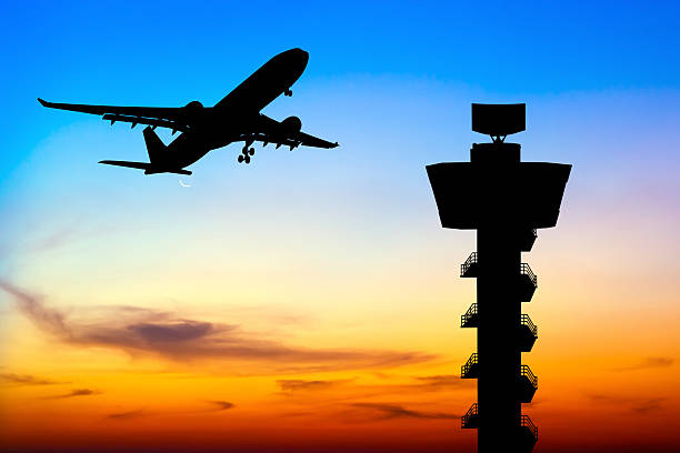 Silhouette commercial airplane take off over airport control tow Silhouette commercial airplane take off over airport control tower at sunset air traffic control tower stock pictures, royalty-free photos & images