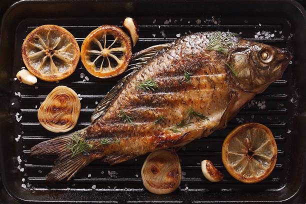 istock carp with lemon, onion, spices on grill pan, top view 486808268