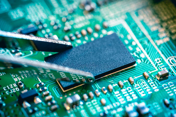 istock Close up on microchip catching with tweezers on circuit board. 486810578