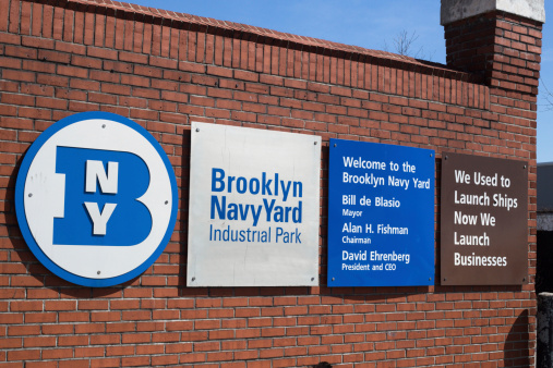 Brooklyn, New York, USA - April 19, 2014: Entrance signs at main gate of historic Brooklyn Navy Yard. This landmark shipyard dates back to the early 1800's.