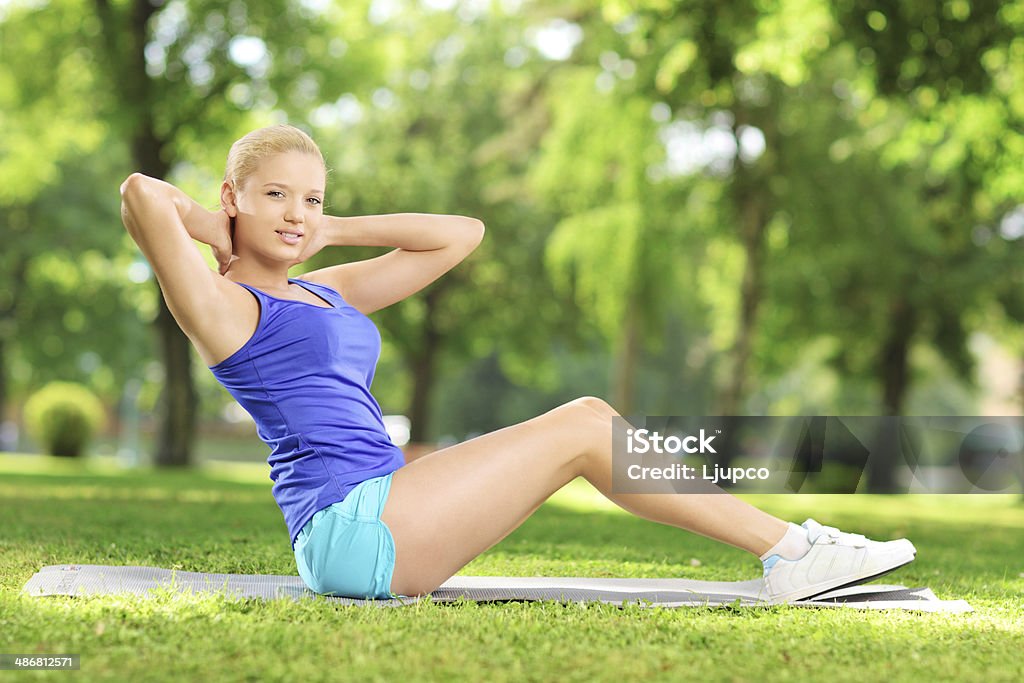 Mujer joven haciendo ejercicios de alfombra en un parque - Foto de stock de 20 a 29 años libre de derechos