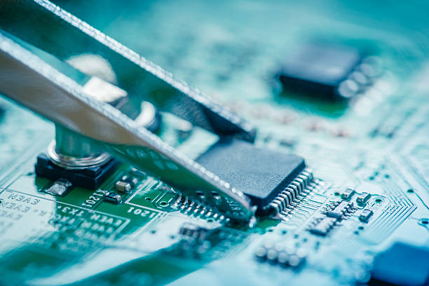 istock Close up on microchip catching with tweezers on circuit board. 486813260
