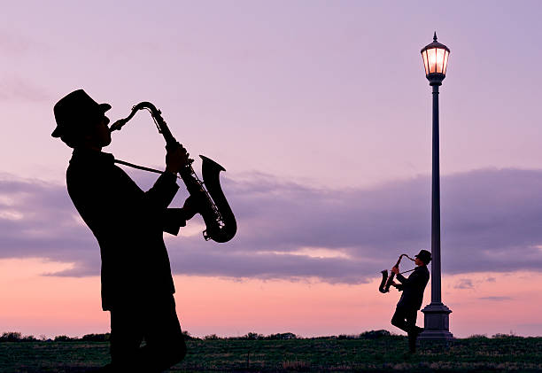 due giovani giocare saxophones accanto a strada lampada - smooth jazz foto e immagini stock