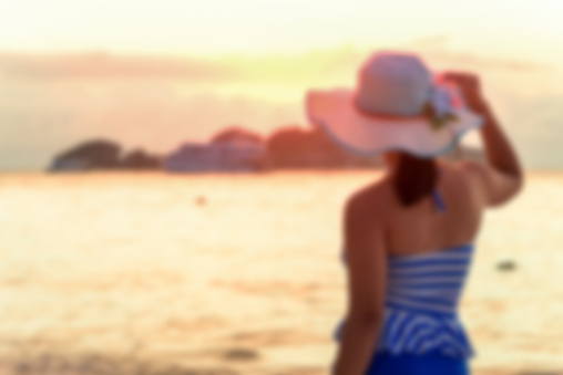 Blurred image for background, Tourist woman in a swimsuit watching sunrise on the beach and sea at Miang island in Mu Koh Similan National Park, Phang Nga Province, Thailand