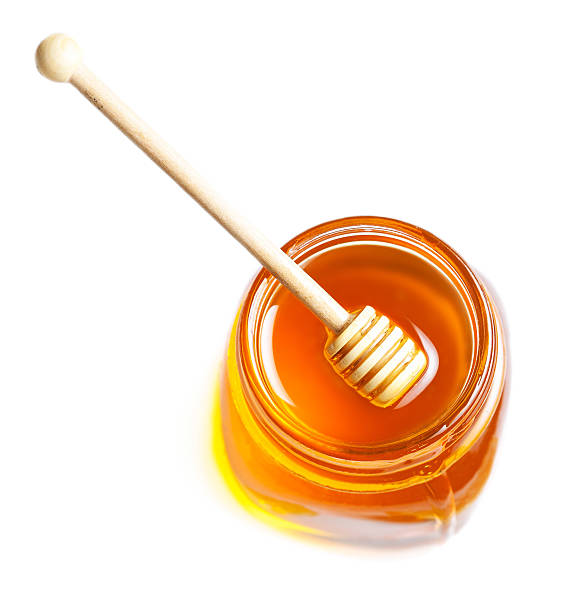 istock Dipping with honey in glass jar isolated on white 486820114