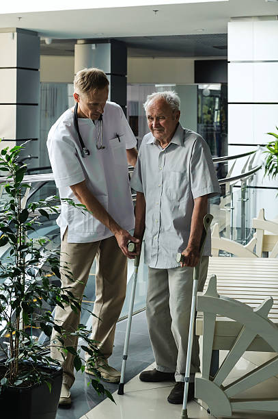 istock Doctor helping elderly man to walk on crutches 486827628