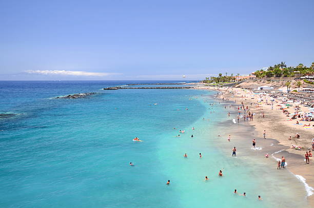 Costa Adeje, Tenerife, Spain - July 20, 2015: Gorgeous sandy Del Duque beach. Playa del Duque has soft golden sand and azure waters.  Originally it was composed of black volcanic sand. 