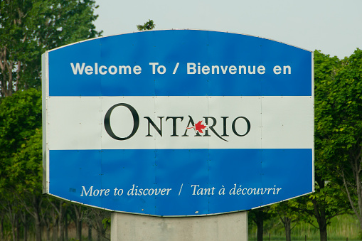 Toronto, Canada - August 23, 2023: Traffic heads west on Highway 401 near Exit 373 to Leslie Street. Overcast skies in the Henry Farm neighborhood north of Highway 401. Upscale residential buildings line the Bayview Village neighborhood in the background.