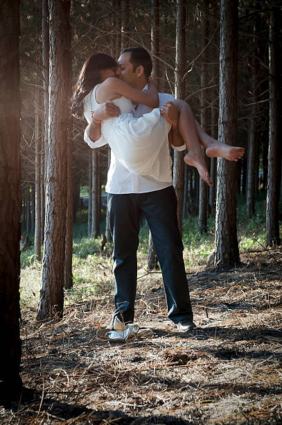 Young indian couple wearing white kissing in forest stock photo