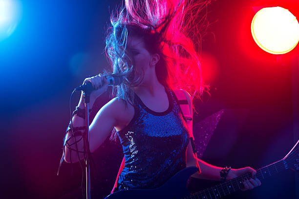 Rock star singing on stage Young rock star singing with stage lights on background. rock musician stock pictures, royalty-free photos & images