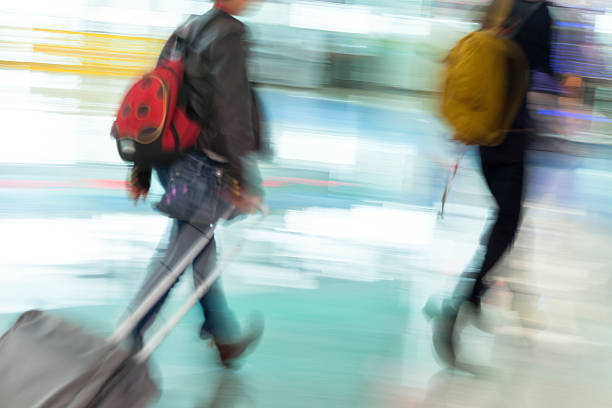istock Motion Blurred Travellers Rushing at Airport Pulling Luggage 486832138