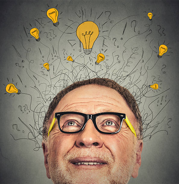 Thinking elderly man with light idea bulb above head Thinking elderly man with question signs and light idea bulb above head looking up on gray wall background man with a light bulb over his head stock pictures, royalty-free photos & images