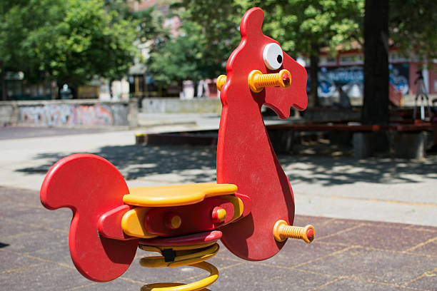 Red Plastic horse toy in a public park. Children love to play with it, because it goes back and forth when you swing