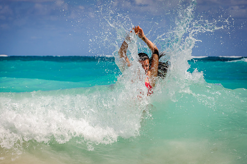 A woman in a wave splash in the Caribbean sea