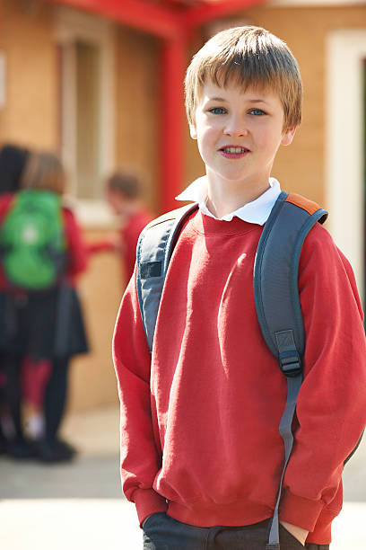 istock Boy Wearing Uniform Standing In School Playground 486836059