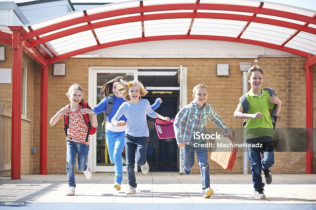 Schoolchildren działa na plac zabaw w momencie zakończenia zajęć - Zbiór zdjęć royalty-free (Wykształcenie)