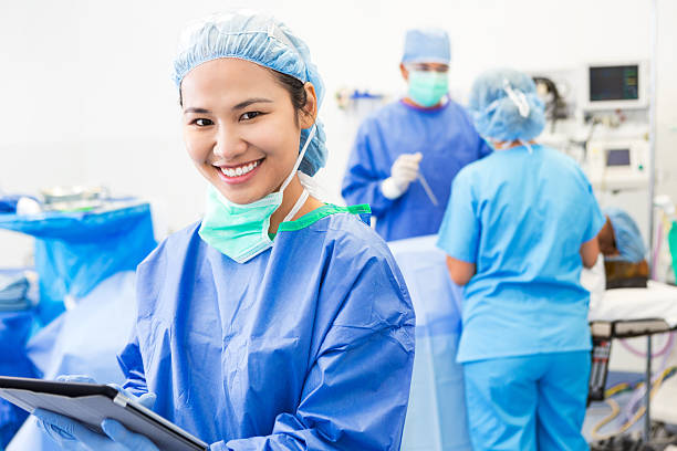 азиатские хирурга или медсестра с помощью цифрового планшета в операционной номер - hair net nurse scrubs asian ethnicity стоковые фото и изображения