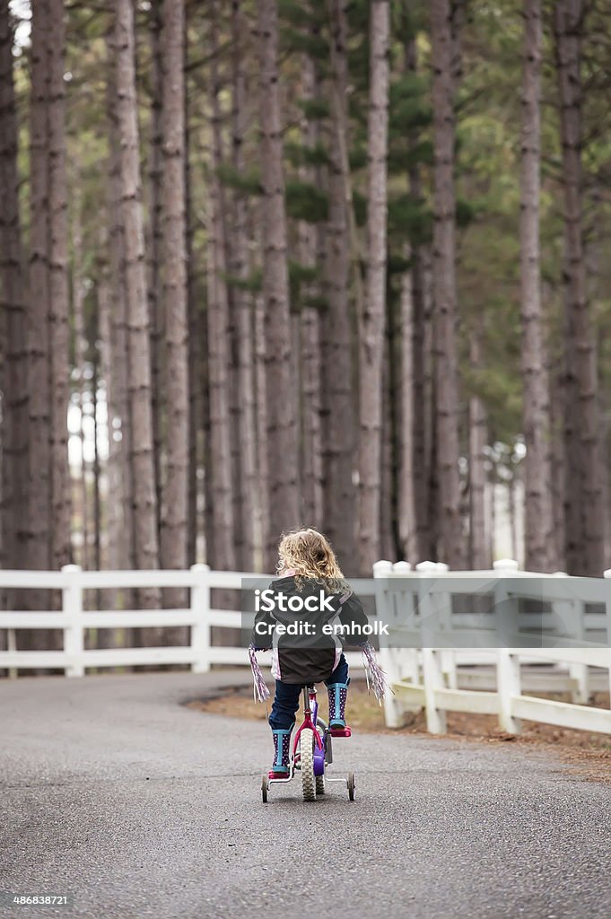 Girl Riding Bike Young girl riding her bike down a rural driveway. 4-5 Years Stock Photo