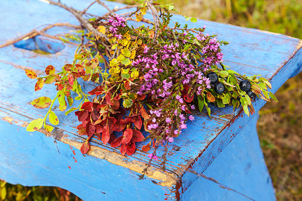 Bouquet of blueberry and heather in the colors of autumn on blue footstool outdoor on a sunny day.