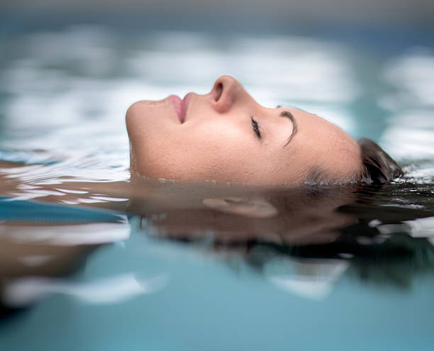 Woman at the spa relaxing at the swimming pool Woman at the spa relaxing at the swimming pool floating with eyes closed hydrotherapy stock pictures, royalty-free photos & images