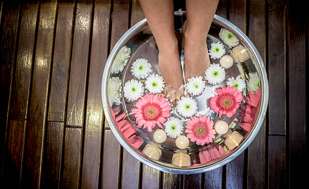 Woman at the spa with feet in water Woman at the spa with feet in water with flowers and candles and getting a foot massage foot spa treatment stock pictures, royalty-free photos & images