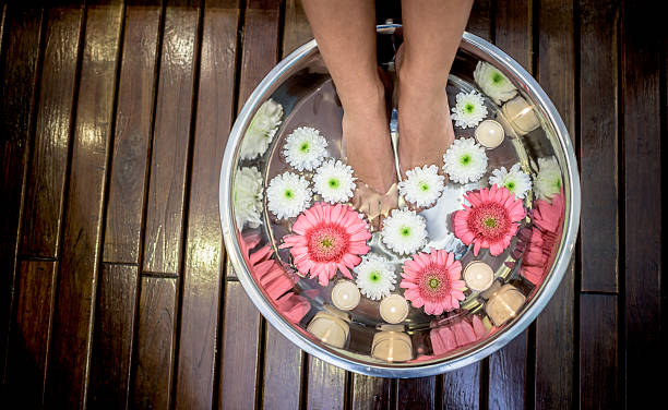 woman at the spa with feet in water - reflexology pedicure massaging human foot imagens e fotografias de stock