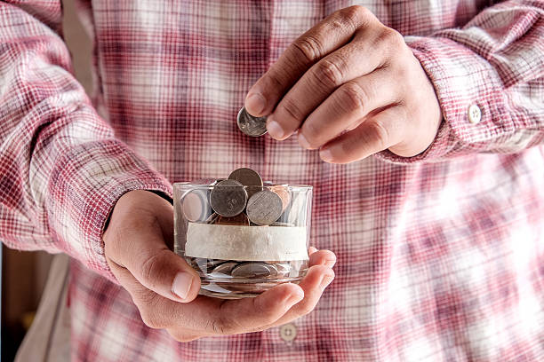 istock man holding money jar with coins close up 486854488