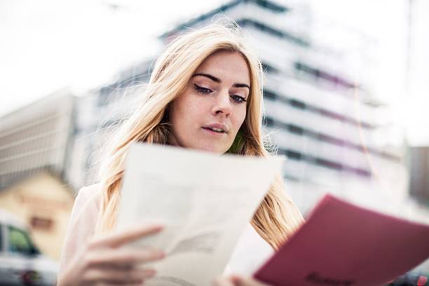 Woman holding and filling papers during lunch break in London, UK.