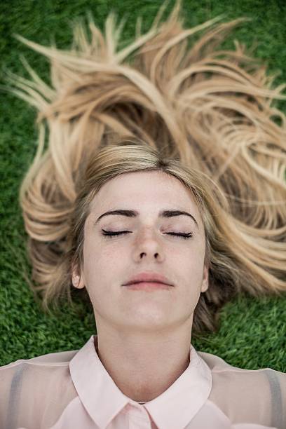 istock Young woman sleeping laying on grass 486857698