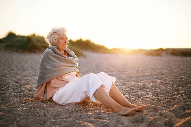 istock Relaxed elderly woman sitting on the beach 486858777