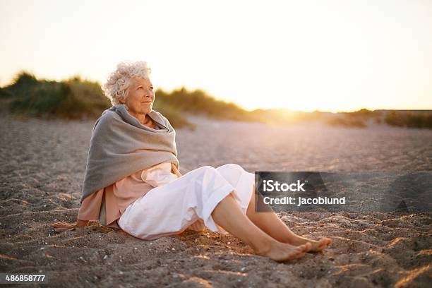 Relaxed Elderly Woman Sitting On The Beach Stock Photo - Download Image Now - Mature Women, Sitting, Beach