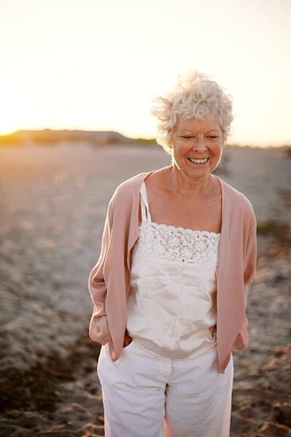 istock Happy mature woman walking on the beach 486858789