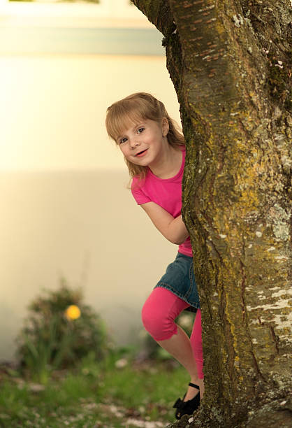 istock Little girl  peeking out from behind a tree. 486862707