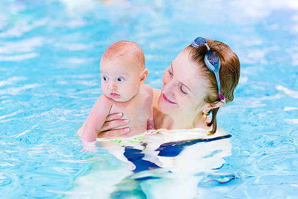 istock Young active woman enjoying swimming pool with baby boy 486863113