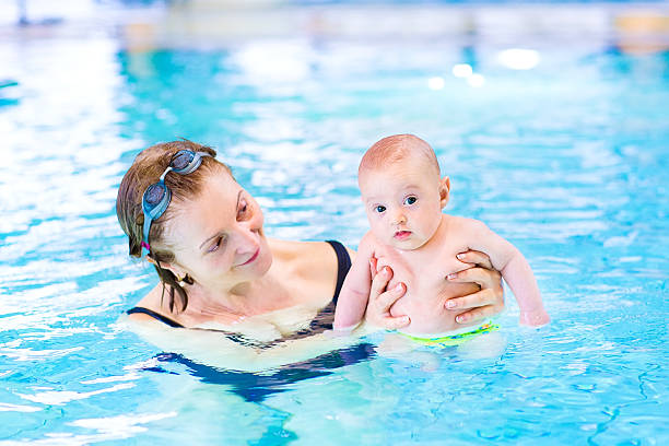 istock Active woman and cute baby having fun in swimming pool 486863169
