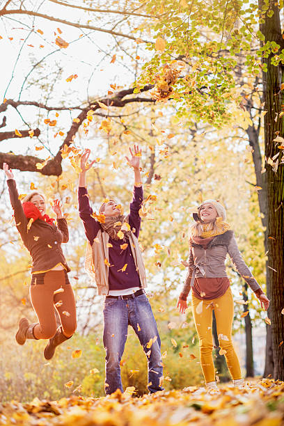 istock Playful friends throwing leaves in park during autumn. 486863302