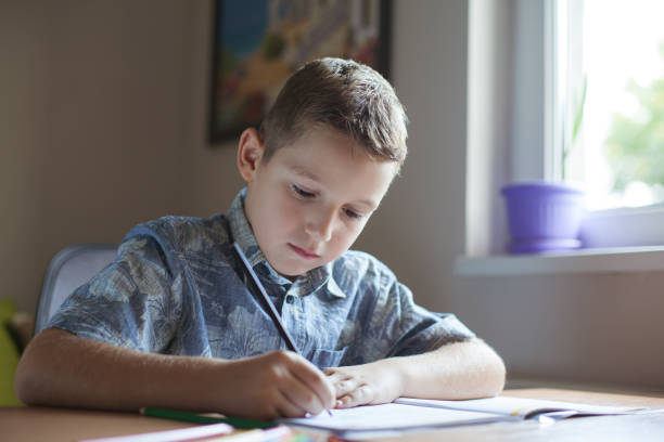 istock Young boy sitting at the table doing his school homework. 486863346
