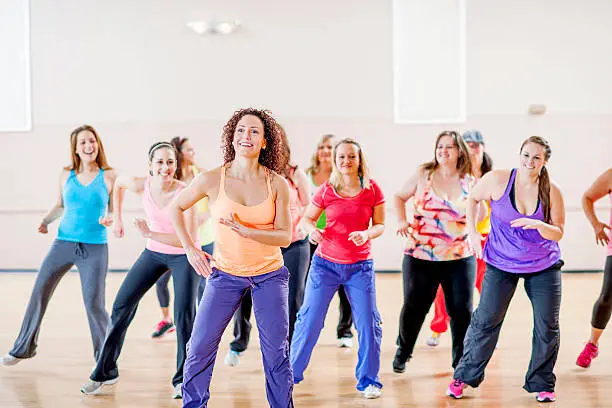 Woman dancing together during an aerobic fitness class - they are smiling and moving to the music.