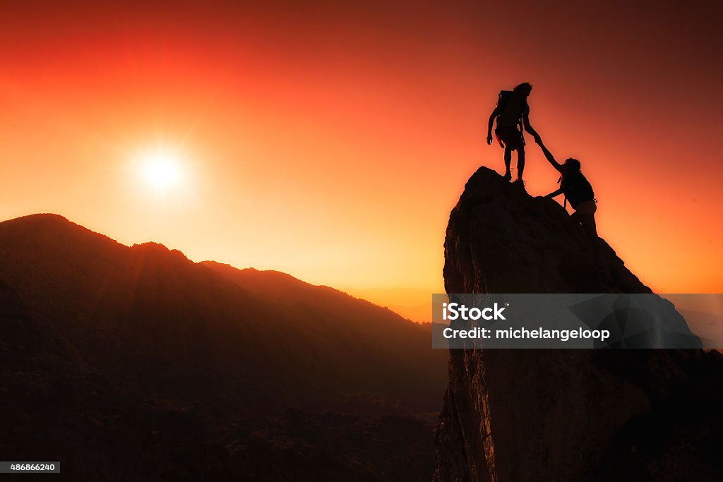Team of climbers help to conquer the summit Team of climbers help to conquer the summit in teamwork in a fantastic mountain landscape at sunset Assistance Stock Photo