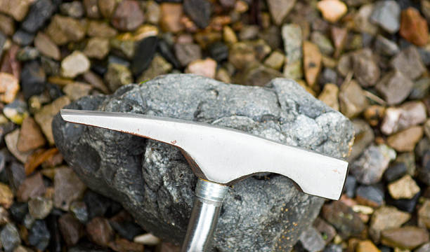 Geology hammer on a grey stone that could contain a fossil from the Jurassic Coast.