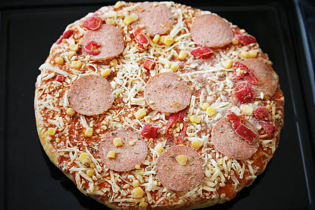 Frozen pizza with salami, cheese, corn and pepper stock photo