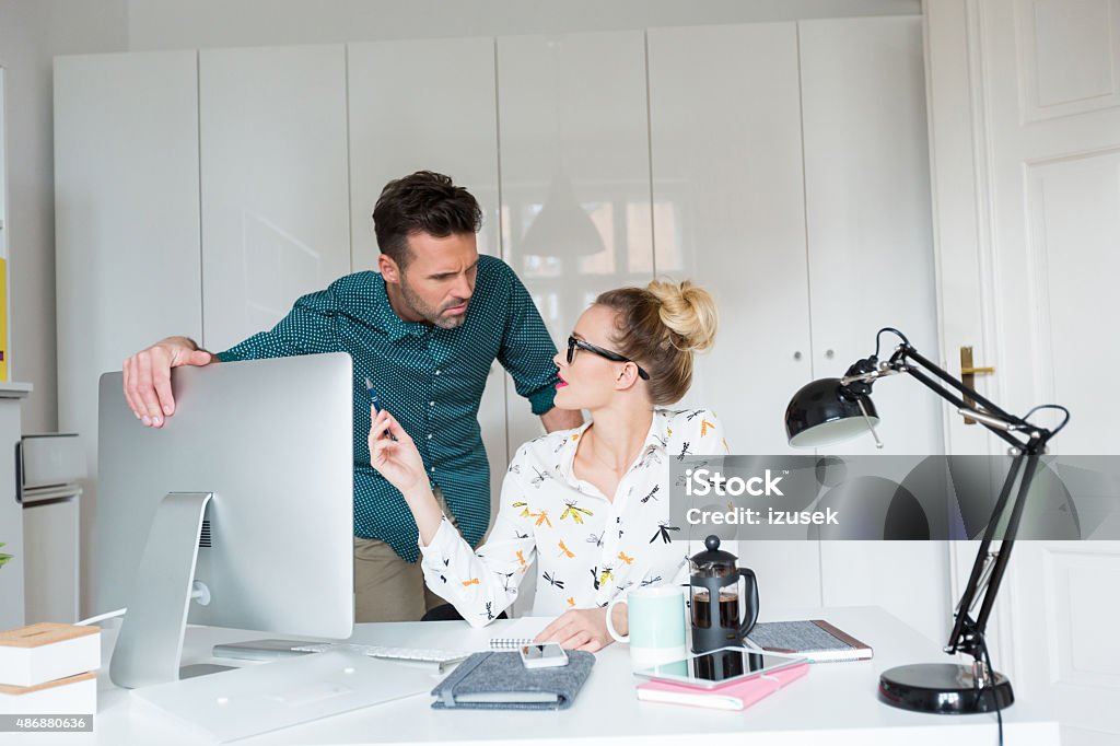 Woman and man working in an office Blonde woman sitting at the desk in an office and talking with her colleague. Businessman Stock Photo