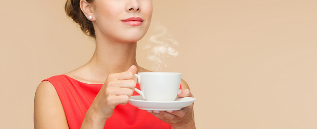 leisure, happiness and drink concept - smiling woman in red dress with cup of coffee